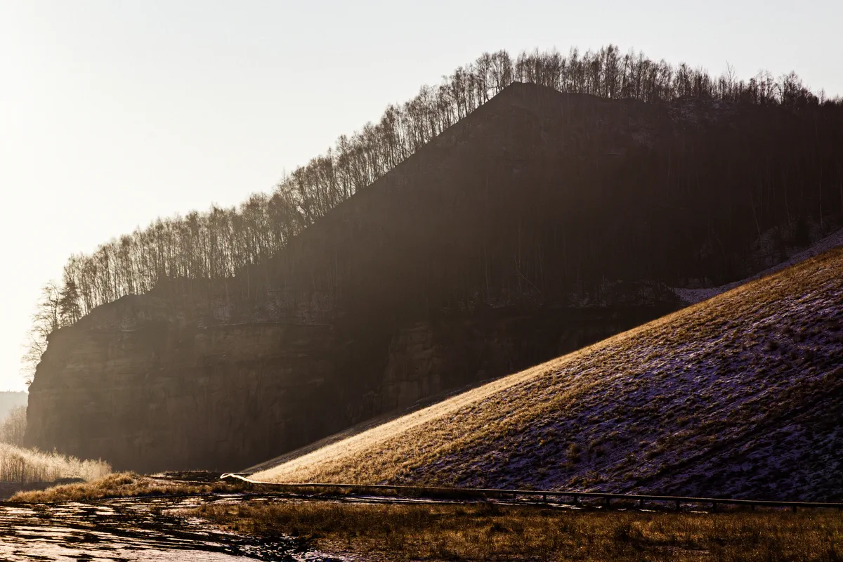 Carrière Barrois, Freyming-Merlebach. Vue du terril de profil, en hiver et à contre-jour. On distingue nettement les arbres qui reprennent le pouvoir sur la colline de schiste (colline artificielle constituée de déchets de l'exploitation).. Ancien site industriel appartenant aux HBL (la compagnie d'extraction du charbon), le site est aujourd'hui une réserve de biodiversité et un lieu de balade.