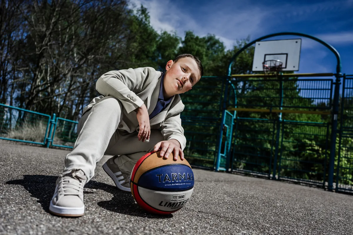 Portrait de Communion dynamique d’un enfant jouant au basket sur un terrain de la Coulée verte à Stiring-Wendel.